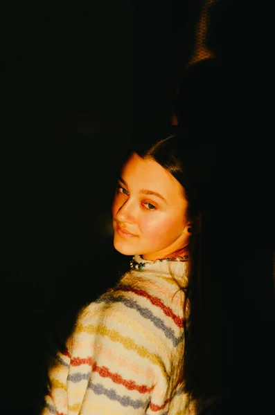 High contrast portrait of young dreamy teen girl standing half-turned in the ray of sunset light looking away. — Stock Photo, Image