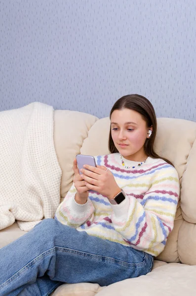 Fiatal tini lány pihen a kanapén, okostelefon digitális eszköz otthon. SMS, közösségi média, online vásárlás. — Stock Fotó