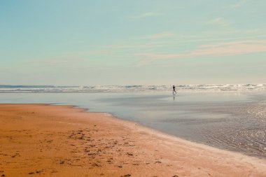 Mawgan Porth plajındaki yalnız koşucunun silueti, Cornwall, İngiltere