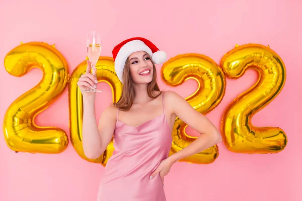 Lächelndes Weihnachtsmädchen hebt ein Glas Champagner in die Höhe. Goldene Zahlen Luftballons Neujahrskonzept — Stockfoto
