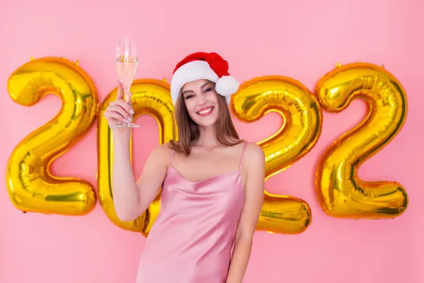 Halbe Länge lächelndes Mädchen hebt Glas Champagner in Santas Hut — Stockfoto
