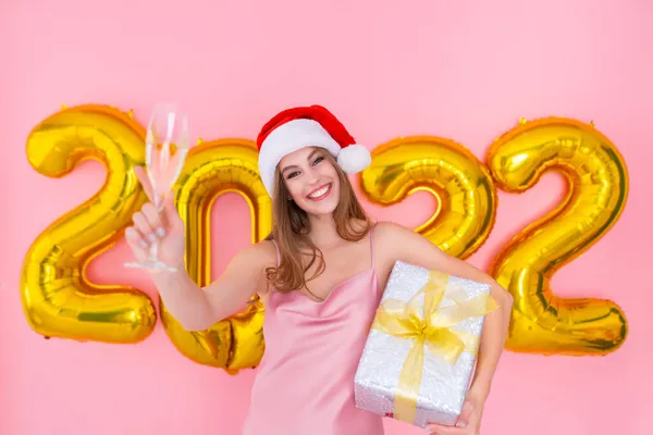 Le Santa flicka höjer glas champagne medan håller presentförpackning. 2022 luftballonger nyår — Stockfoto