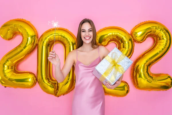 Glückliches Weihnachtsmädchen hebt Champagner in die Höhe und hält Geschenkbox in der Hand. Luftballons zum Jahreswechsel 2022 — Stockfoto