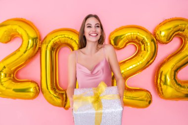 Heyecanlı kız, gümüş hediye kutusunu 2022 hava balonlarında izole bir şekilde tutuyor.