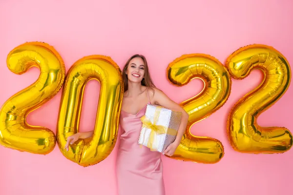 Lächelndes Mädchen steht neben Luftballons mit Geschenkverpackung auf rosa Hintergrund. Neujahrsfeier — Stockfoto