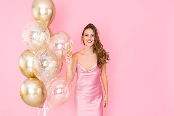 Lächelndes Mädchen hebt ein Glas Champagner in die Höhe, während es in der Nähe von Luftballons steht. kam zum Feiern. Feier — Stockfoto
