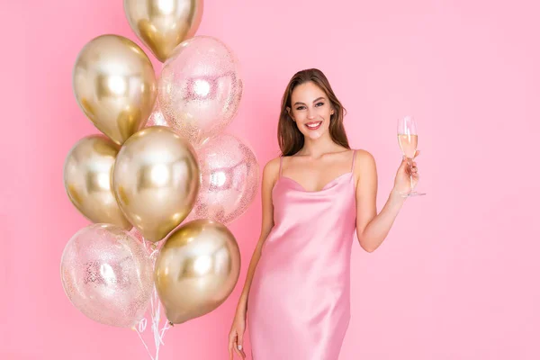 Lächelnde junge Frau hält ein Glas Champagner in der Nähe von Luftballons. kam zum Feiern. Feier — Stockfoto