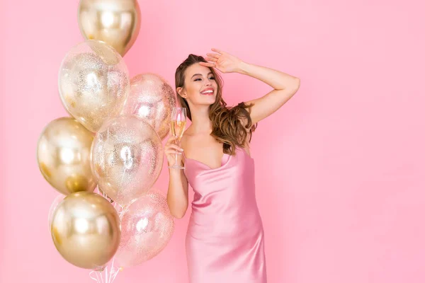 Glückliche junge Frau hält ein Glas Champagner in der Nähe von Luftballons. kam zum Feiern. Feier — Stockfoto