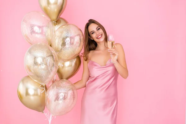 Una joven sonriente sostiene una copa de champán y globos dorados. vino a la fiesta. Celebración — Foto de Stock