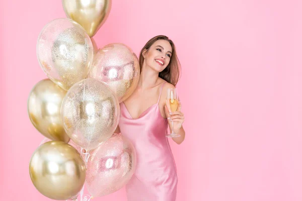 Lächelnd hält ein fröhliches Mädchen ein Glas Champagner und viele Luftballons in der Hand. kam zum Feiern. Feier — Stockfoto