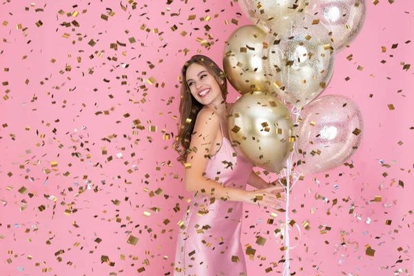 微笑的女孩一边拿着许多气球，一边拿着五彩纸屑庆祝新年或生日快乐 — 图库照片