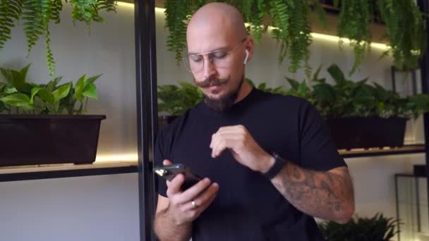 Biały biznesmen używa telefonu komórkowego, gdy stoi w kawiarni. Koncepcja wolnego strzelca — Wideo stockowe