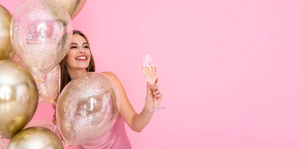 Glückliches Mädchen hält Champagner, Luftballons auf buntem Hintergrund. Geburtstag Neujahrsfeier. — Stockfoto