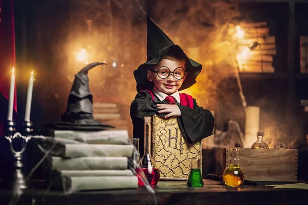 Small wizard in glasses, wizards hat holds magic book. Cosplay. Looking at camera. Halloween party