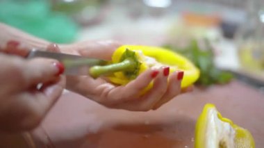 Kadın ev mutfağında salata hazırlıyor. 4K yakın çekim videosu. Kadın yemek tabağı: biberli biber biberi, masada sebze. Sağlıklı yemek.