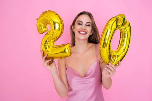 Young teenager smiling girl holds gold foil balloon on pink background. BIRTHDAY PARTY concept