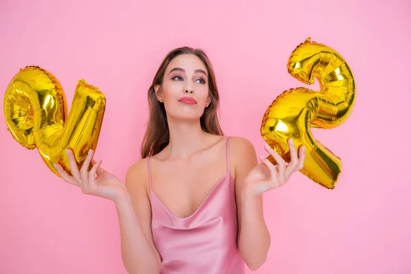 Giovane donna in divertimento tiene palloncino foglio d'oro isolato su sfondo rosa. CONCLUSIONI DI BIRTHDAY PARTY — Foto Stock