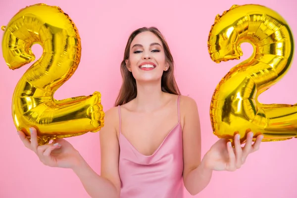 Feliz joven mujer sostiene globo de lámina de oro aislado sobre fondo rosa. FIESTA DE CUMPLEAÑOS — Foto de Stock