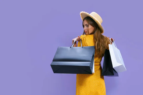 Вид ззаду жінка тримає пакети після покупки на фіолетовому тлі. знижка, чорна п'ятниця, продажі — стокове фото