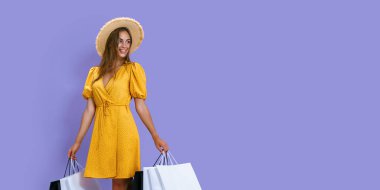 Moda tutkunu bir kız mor arka planda alışveriş yaptıktan sonra paketleri tutar. İndirim, Kara Cuma, satış