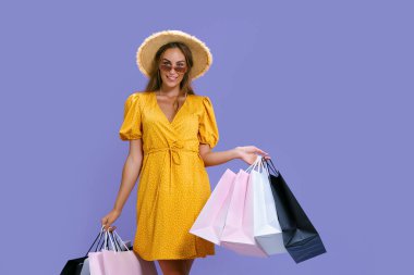 Şapkalı ve güneş gözlüklü mutlu kadın kameraya gülümserken alışveriş yapıyor. Kara Cuma, büyük satışlar. 