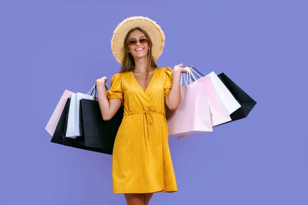Chica de aspecto agradable lleva ropa mientras sostiene paquetes de colores sobre fondo púrpura. grandes ventas —  Fotos de Stock