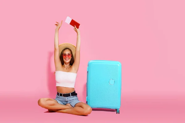 Happy young woman with suitcase, tickets, money and passport are going to travel. Travel concept