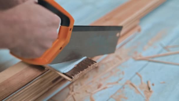 Vista cercana del carpintero no identificado cortando una tabla de madera con sierra manual. Taller de carpintería — Vídeo de stock