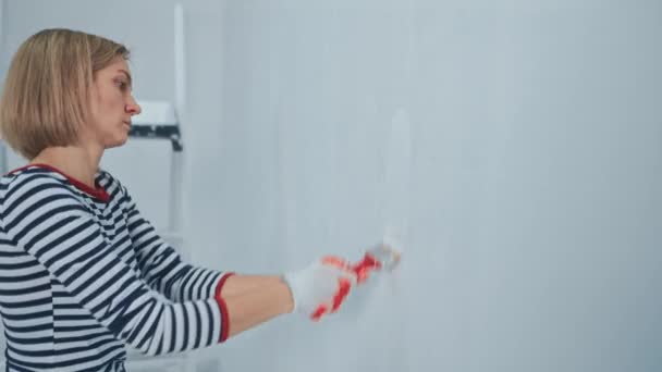 Dělnice používající štětcem natírání stěn v bytě nebo domě. Stavba, opravy a renovace