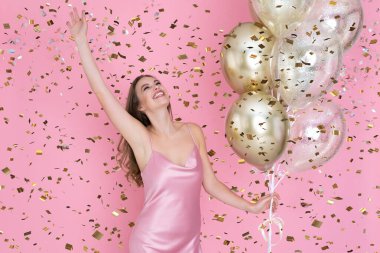 Mutlu genç kadın yeni yılı kutluyor ya da mutlu yıllar partisi hava balonları konfeti atıyor..