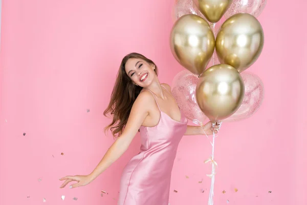 Chica celebra año nuevo o feliz cumpleaños fiesta sostiene globos de aire en vestido brillante lanzando confeti — Foto de Stock