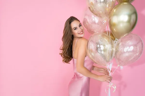 Mädchen feiert Neujahr, Geburtstag oder 8. März Party, während hält viele Luftballons auf rosa Hintergrund — Stockfoto