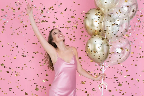 Felice giovane donna festeggia il nuovo anno o felice festa di compleanno tiene palloncini d'aria lancio coriandoli. — Foto Stock