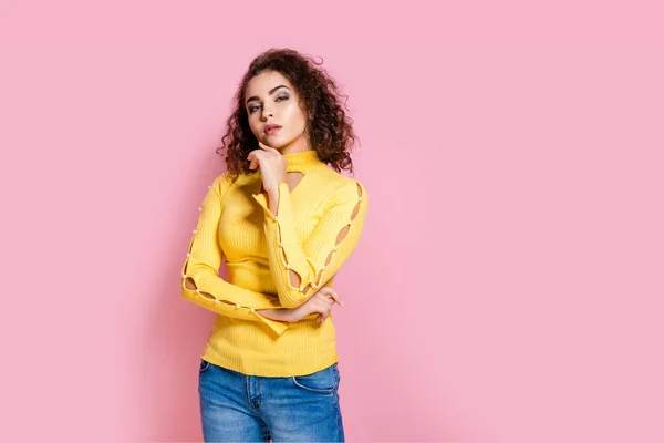 Potret gadis kurus termenung dengan pakaian kuning meletakkan tangan di dagu terisolasi di latar belakang merah muda — Stok Foto