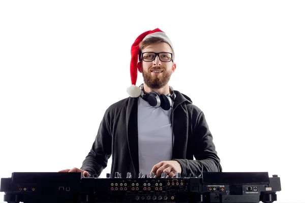 Bearded dj in christmas hat, glasses plays music on a turntable while isolated on white background — Stock Photo, Image