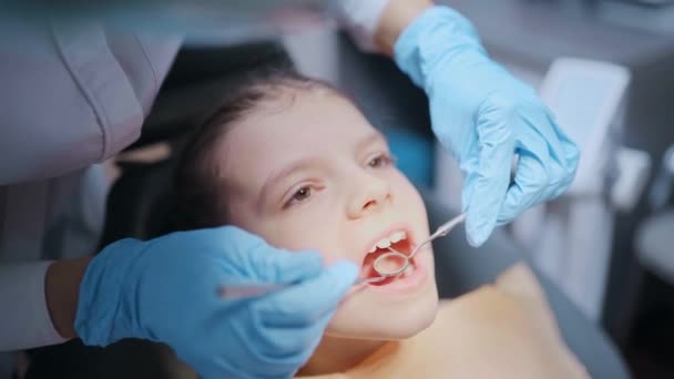 Close up face do littel menina paciente com boca aberta durante exame dentário até condição dos dentes. — Vídeo de Stock