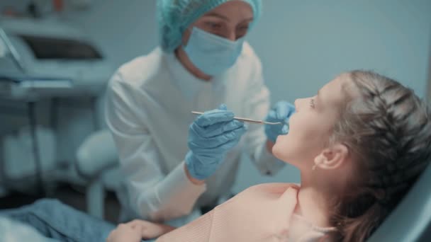 Diş kontrolü sırasında diş hekimliği yaparken ağzı açık oturan küçük kız.. — Stok video