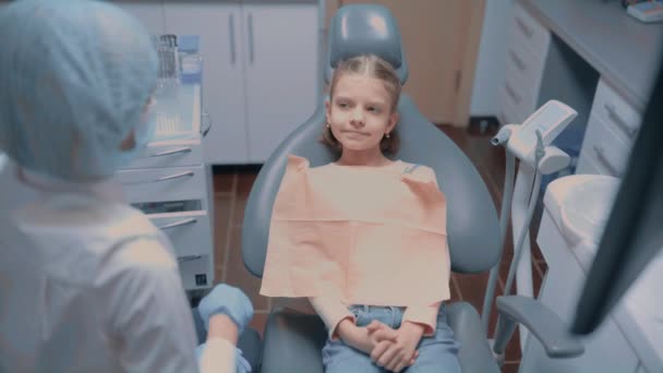 Dost canlısı dişçi muayene sonrası stomatoloji sandalyesinde oturan beş küçük hastayı selamlıyor. — Stok video