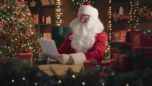 Santa Claus, Saint Nicholas läsa bokstäverna noga när du sitter vid bordet hemma — Stockvideo