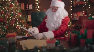 Duygusal Noel Baba mektupları okur, el kol hareketi yapar ve evde masada otururken konuşur.