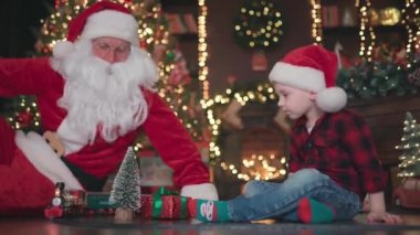 Küçük çocuğun Noel Baba 'yla birlikte, Noel ağacının altında demiryolu ile oynadığı video. 