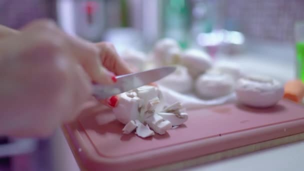 절판에 잘게잘게 썬 샹 폴리논 버섯을 클로즈업한 것입니다. 여성의 손 이 버섯을 자르고 있습니다. 백인 여자가 요리를 한다 — 비디오