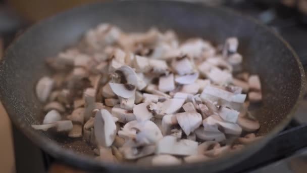Куски грибов поджариваются на сковороде. Шампиньоны, обжаренные в масле — стоковое видео