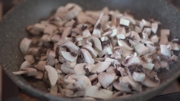 Шматочки грибів смажать на сковороді. Нарізані печериці, обсмажені в олії — стокове відео