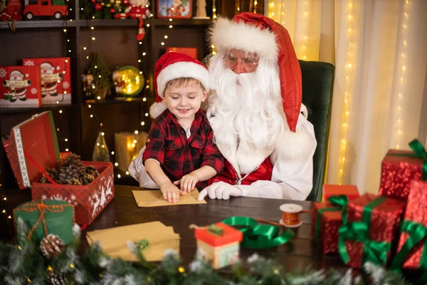 Санта Клаус з маленьким хлопчиком-асистентом відкриває конверти з різдвяними побажаннями. Святкова концепція — стокове фото