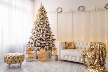Yeni yıl ağacının süslendiği beyaz bir Noel arması. Altın puf, tekstil, ağacın altında hediyeler.