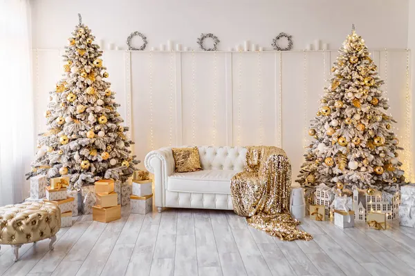Белый современный интерьер с украшенными новогодними деревьями. Золотой пуф, текстиль, подарки — стоковое фото