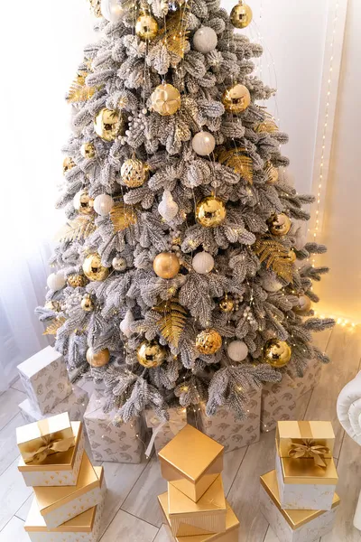 Karácsonyi ajándékok szilveszteri fa alatt mesterséges hó arany megvilágítással. Arany szín.. — Stock Fotó