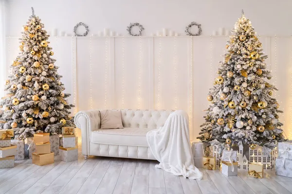 Interior da sala de estar branca com árvores de Ano Novo decoradas, caixas de presente e sofá moderno. Cor dourada — Fotografia de Stock