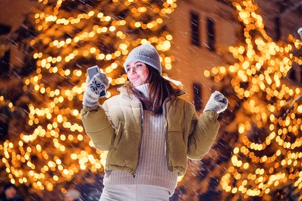 Glimlachend volwassen meisje neemt selfie buiten terwijl staan in de voorkant van kerstvakantie decoraties — Stockfoto